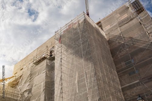 Foto Building renovation with scaffolding and protective mesh