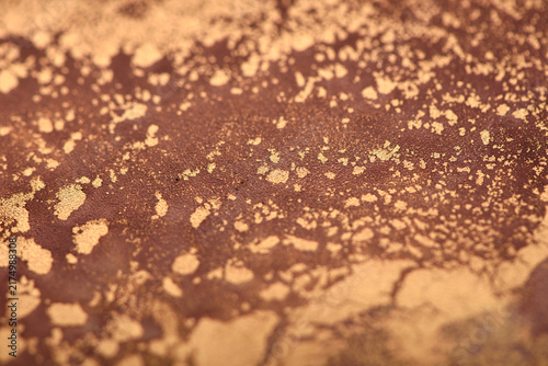 Artistic background featuring reddish-brown swirls with gold accents; photo of the surface.