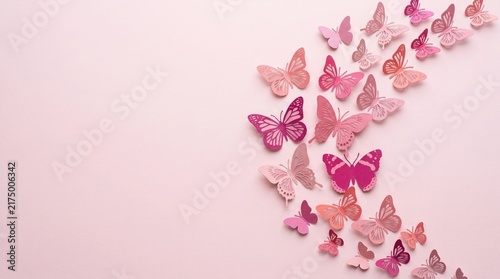 A beautiful composition of many small pink paper butterflies arranged in a crescent shape on a pink background