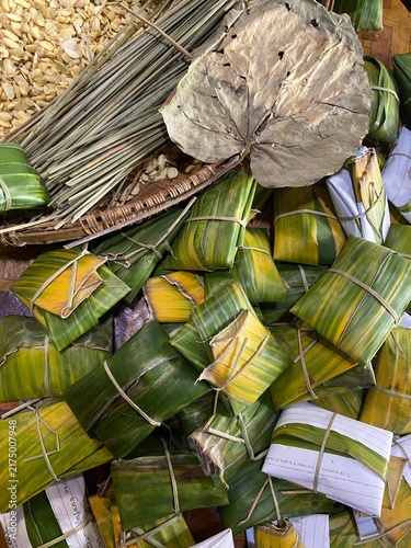 Canvastavla Handmade tempe parcels in progress, tightly wrapped in green banana leaves and secured with bamboo sticks alongside peeled soybeans and traditional tools