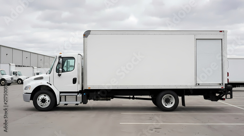 Commercial heavy delivery vehicle parked at a distribution warehouse terminal during an overcast day ready for transporting freight cargo goods across the country for logistics and supply chain