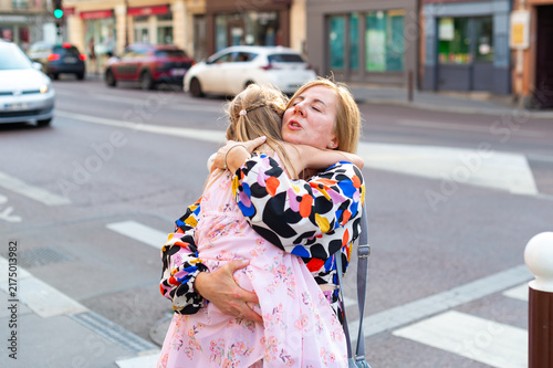 Foto A mother holds and hugs her young daughter on a city sidewalk in Paris, France