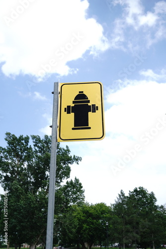 Cuadro en lienzo A yellow sign with a black silhouette of a fire hydrant mounted on a metal pole