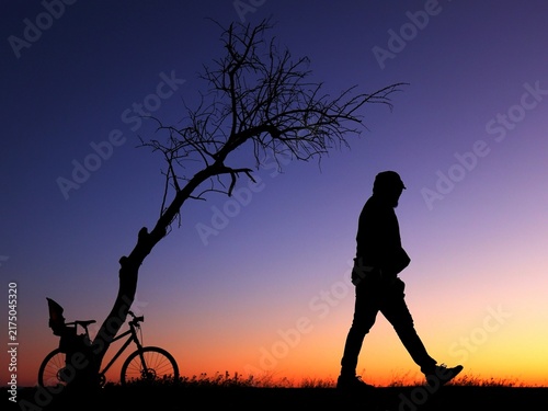 Fotografie Silhouette d'un homme marchant  seul le soir avec détermination dans une ambiance mystérieuse et un peu effrayante