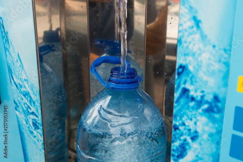Drinking water flows into a reusable bottle at a dispenser, highlighting hydration, refill culture, and environmentally friendly consumption.