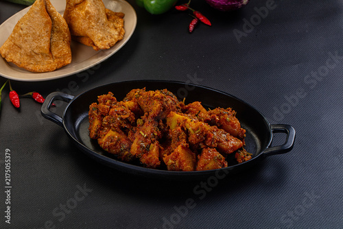 Fotografie Spicy broccoli fry served in black oval dish with samosas and red chilies on dar