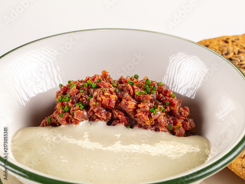 Foto Beef tartare with chives and creamy sauce in white bowl