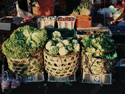 Quadro su tela Fresh green leafy vegetables cauliflowers and bok choy in bamboo baskets at Indo