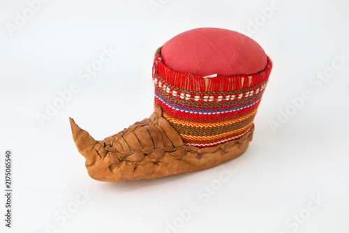 Fotografie Traditional Sami-style pincushion, featuring a distinctive pointed leather slipper base and a vibrant knitted cuff with fringe, set against a clean white background