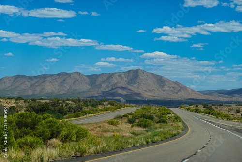 Empty desert highway curving through the arid landscape toward mountains in Arizona, USA.