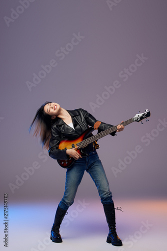 Foto Energetic female bassist playing bass guitar in studio