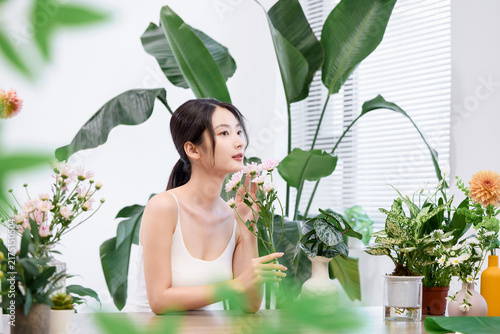 Fotografía Young woman with flowers in bright indoor garden setting