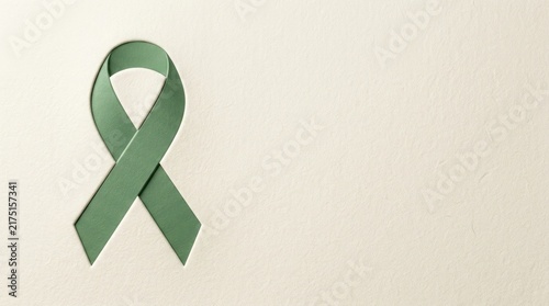 Fototapeta A green awareness ribbon isolated on a plain background for world mental health day campaign and support