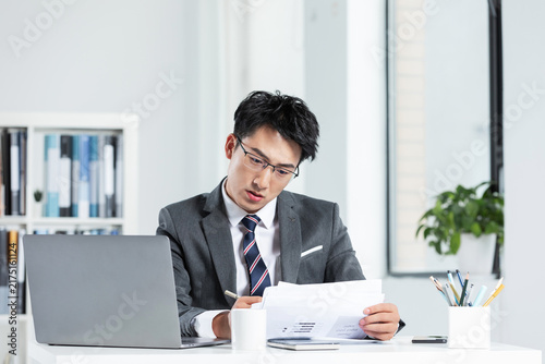 Businessman Reviewing Documents at Desk in Modern Office