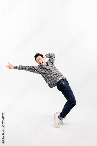 Obraz na płótnie Playful young man making exaggerated leaning gesture on white background