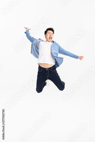 Cuadro en lienzo Excited young man jumping with arms spread on white background