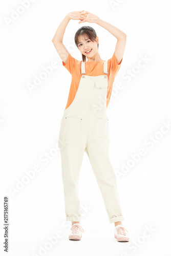 Canvastavla Smiling young woman stretching in overalls on white background
