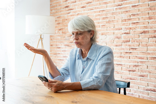 Bild auf Leinwand Senior woman at home experiencing frustration and confusion while trying to use