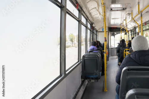 Passengers sit inside a city bus beside large windows. Space for text.
