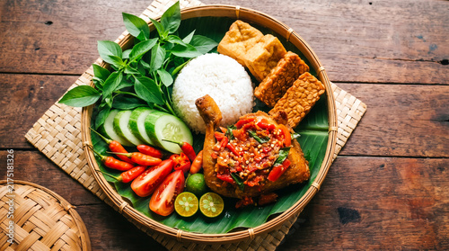 Quadro su tela Traditional Indonesian fresh vegetables topped with spicy sambal chicken, steamed rice, fried tempeh, tofu, fresh basil leaves, sliced cucumbers, tomatoes, and chilies served on bamboo tray