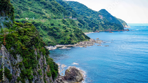 Fotografie 切り立った断崖と深い緑の山肌に沿って広がる青い海岸線