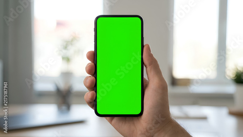 Hand holding smartphone with green screen mockup
