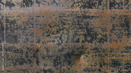 Fotografía Weathered rusty black metal surface with orange corrosion spots under diffuse li