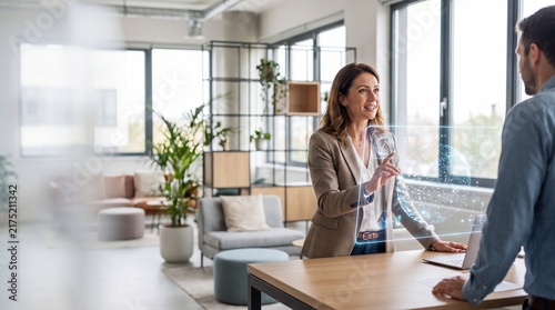 Young Businesswoman Sitting in a Modern Office Lobby Using a Smartphone, Smiling and Communicating, Professional Executive Working in a Contemporary Business Environment