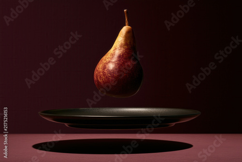 Floating pear over shadowed plate
