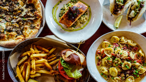 Canvastavla Dining table filled with various dishes including pizza, fish, pasta, tacos, and