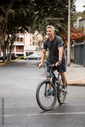 Focused Man Riding Bicycle Along City Sidewalk