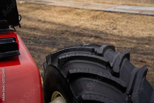 Obraz na plátně Close up of a large agricultural tractor tire with deep rubber tread pattern on muddy field soil, demonstrating high traction farm vehicle equipment
