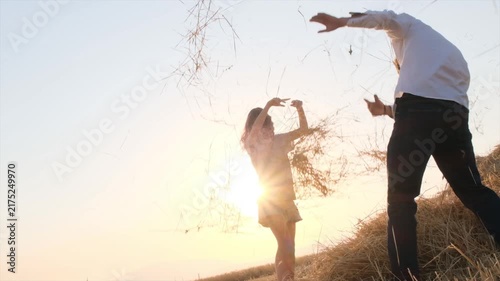 Happy boy and girl playfully throwing wheat straw at each other in a harvested field at sunset, laughing and enjoying life, childhood friendship, carefree youth, positive emotions, rural summer