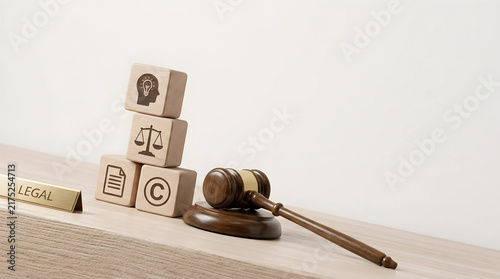 Legal concept of intellectual property shown through a wooden gavel and blocks with copyright and justice icons on a neutral surface.