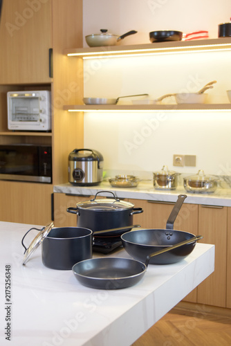 Fotografie Black cookware positioned on a kitchen stovetop, photographed within a warm contemporary interior for a practical cooking concept