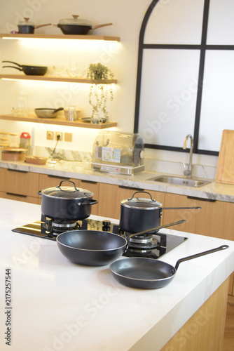Fotografie Dark cookware displayed together in a bright kitchen setting, showcasing practical pans and coordinated home cooking equipment