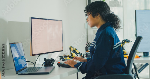 фотографія Young African American female robotics engineer coding AI software for robotic arm in laboratory