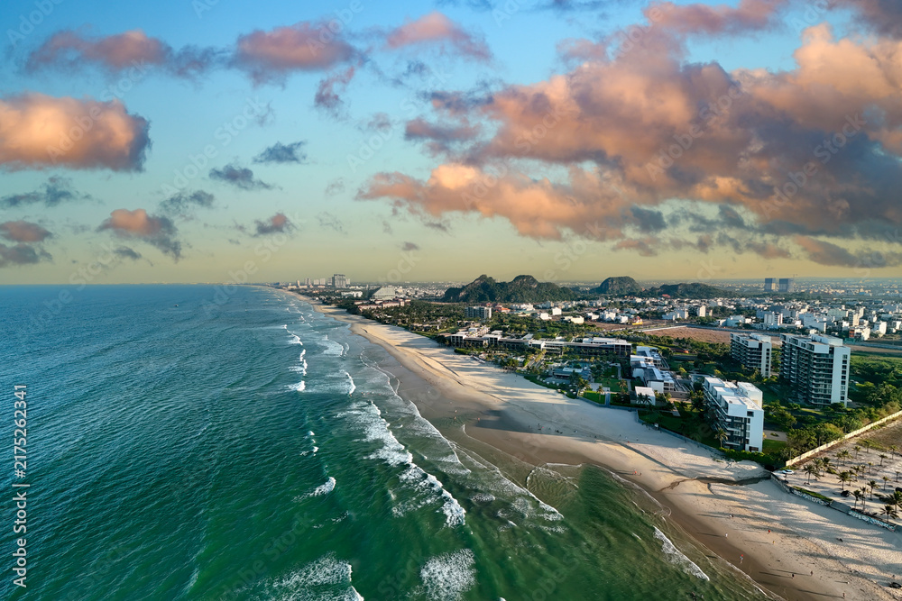 Obraz premium Luxury hotels line the coast of Da Nang in Vietnam while gentle waves wash over the sandy beach under a bright blue sky on a summer afternoon