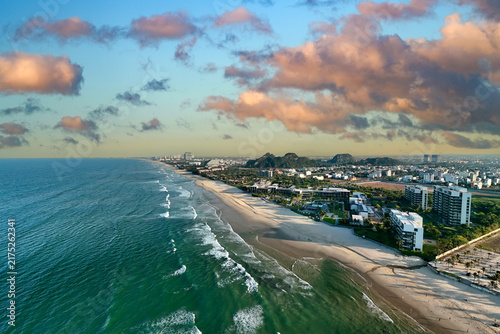 Luxury hotels line the coast of Da Nang in Vietnam while gentle waves wash over the sandy beach under a bright blue sky on a summer afternoon