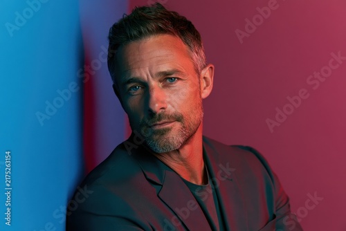 Elegant head-and-shoulders portrait of a mature man on a vivid color wall