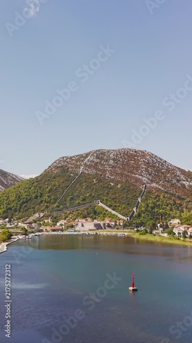 Panoramic view of Ston, Croatia, featuring historic fortress walls, Drums Tower, rugged mountains, traditional red-roofed houses, and the scenic Adriatic coast