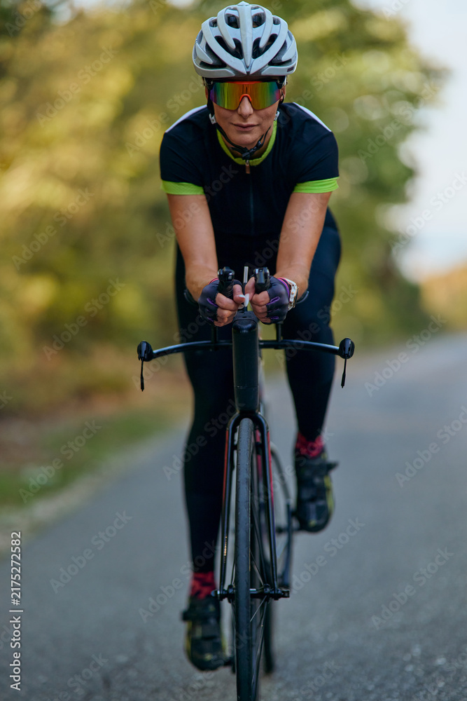 Naklejka premium Female Cyclist Training on Road Bike Wearing Helmet and Sunglasses During Outdoor Fitness Ride