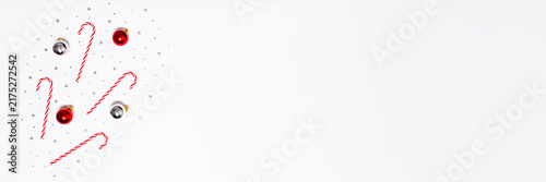 Minimal Christmas background with candy canes, red and silver baubles, confetti on white copy space for festive banners, ads, sales and social media designs