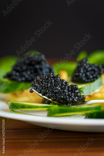 Cuadro en lienzo Black caviar and cucumber served on pancake on wooden background