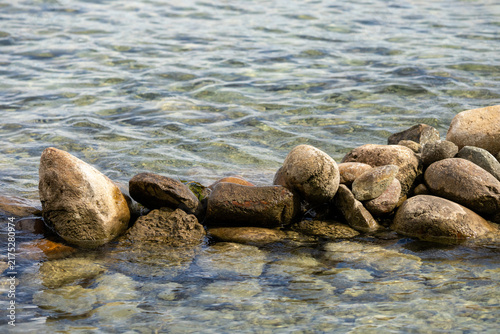 Bild auf Leinwand Clear water gently laps over rounded stones