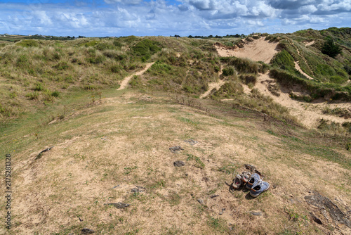 Aerial view of grassy coastal sand dunes with a pair of abandoned hiking boots left on the ground amid winding sandy trails, Padstow, England, UK