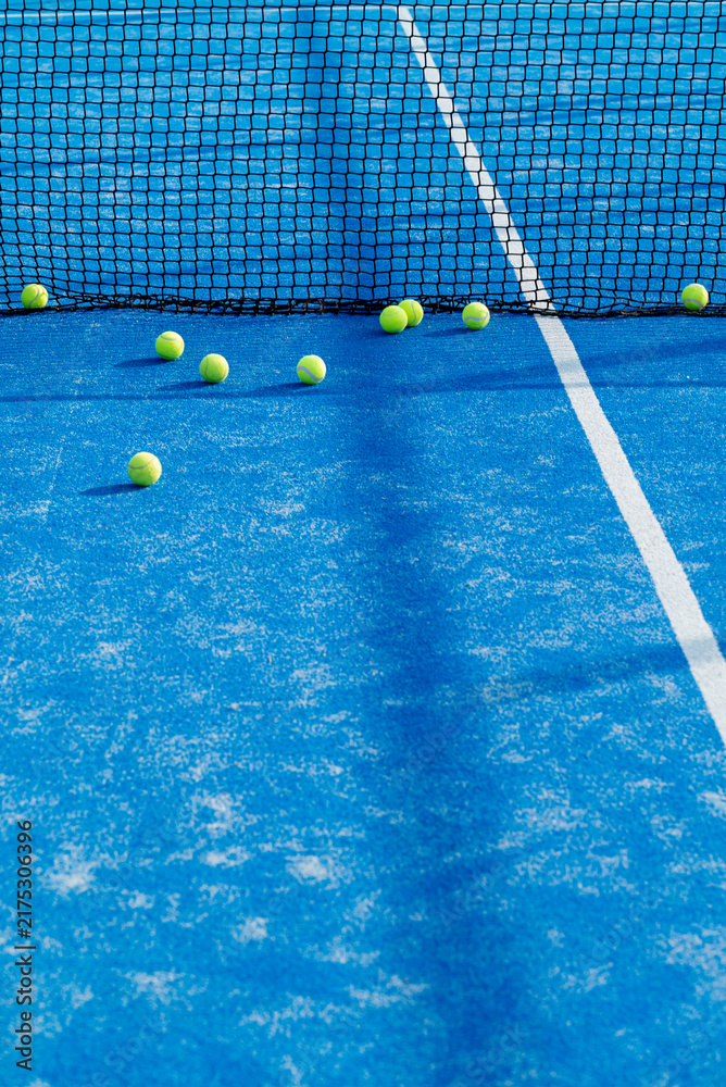 Naklejka premium Tennis balls near black net on blue padel court The Concept of sports training and athletic competition