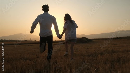 Happy young girl and boy running hand in hand toward the sunset, friendship and youth, optimism and new beginnings, enjoying life in the present moment, carefree outdoor lifestyle, slow motion