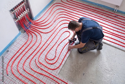 Obraz w ramie Underfloor heating installation worker mounting red pipe system