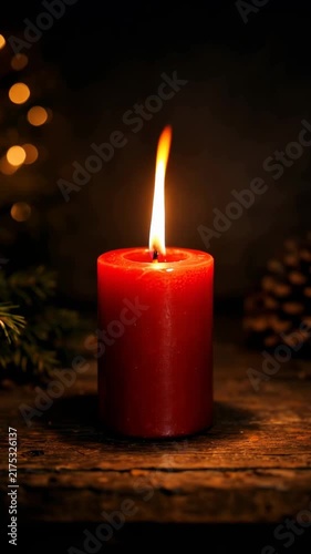 Red candle with a warm flickering flame on a rustic wooden table surrounded by pine cones and festive bokeh lights for holiday ambiance
